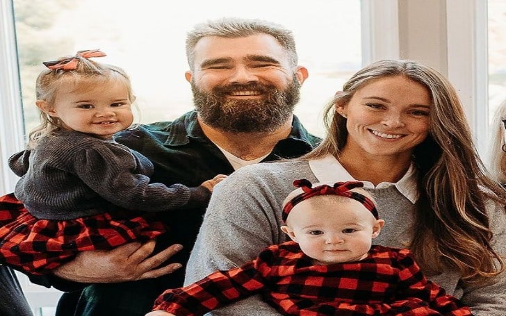 Kylie McDevitt in a grey sweater with her husband and children in red and black checked dresses.